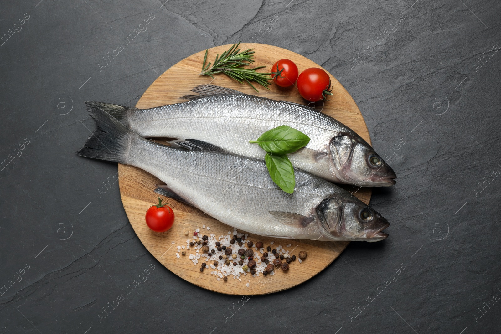 Photo of Sea bass fish and ingredients on black table, top view