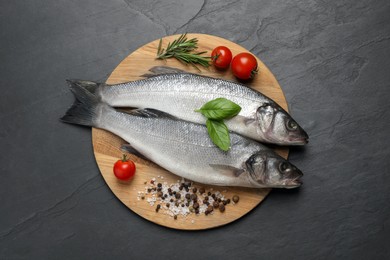 Photo of Sea bass fish and ingredients on black table, top view