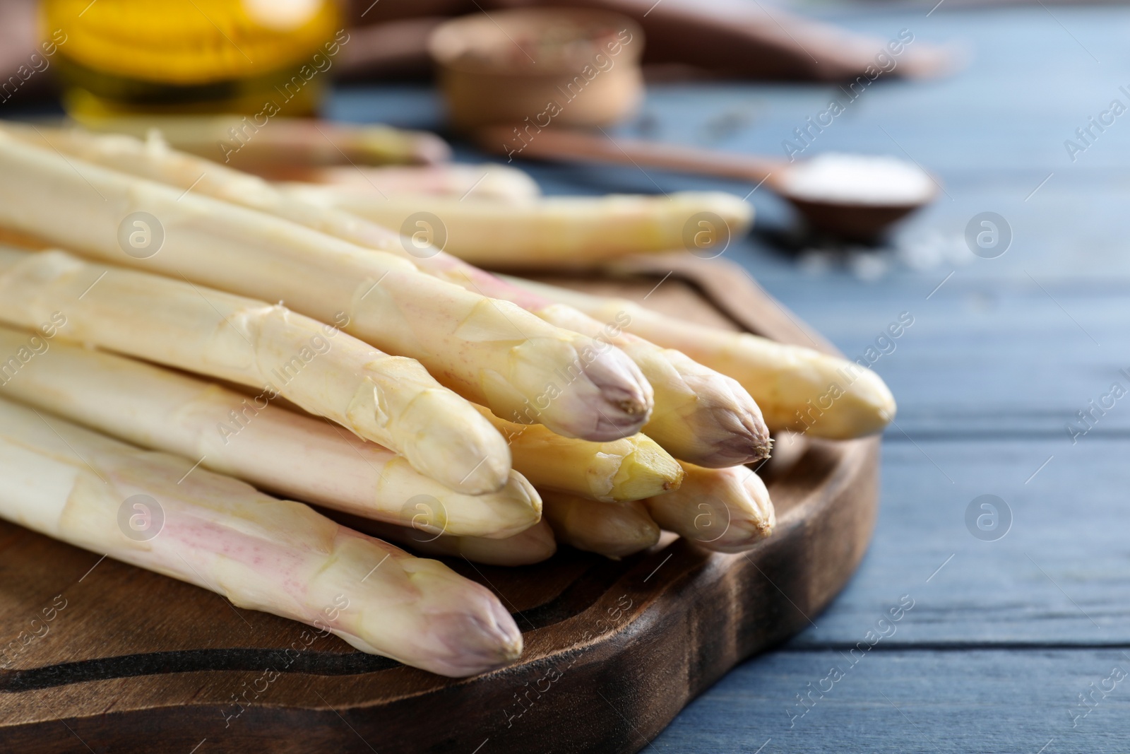 Photo of Fresh white asparagus on blue wooden table, closeup