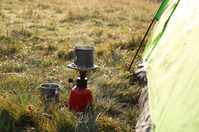 Photo of Portable gas burner with cup near camping tent in mountains