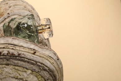 Photo of Luxury perfume in bottle on textured surface against beige background, space for text