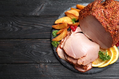 Slate plate with delicious ham and potatoes on grey wooden table, top view. Space for text