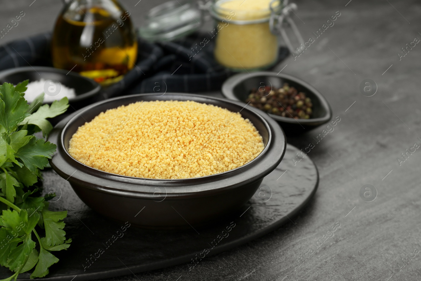 Photo of Raw couscous and ingredients on grey table, closeup