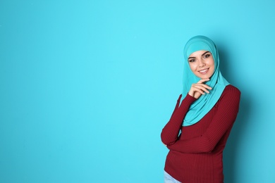 Portrait of young Muslim woman in hijab against color background. Space for text