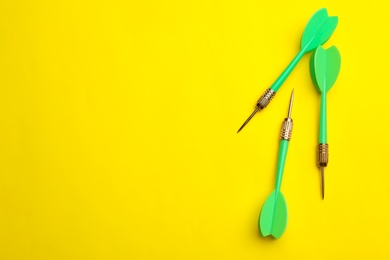 Photo of Green dart arrows on yellow background, flat lay with space for text