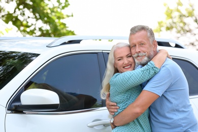 Happy senior couple posing near car outdoors