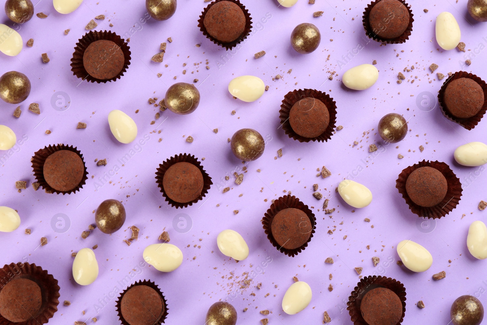 Photo of Different delicious chocolate candies on lilac background, flat lay