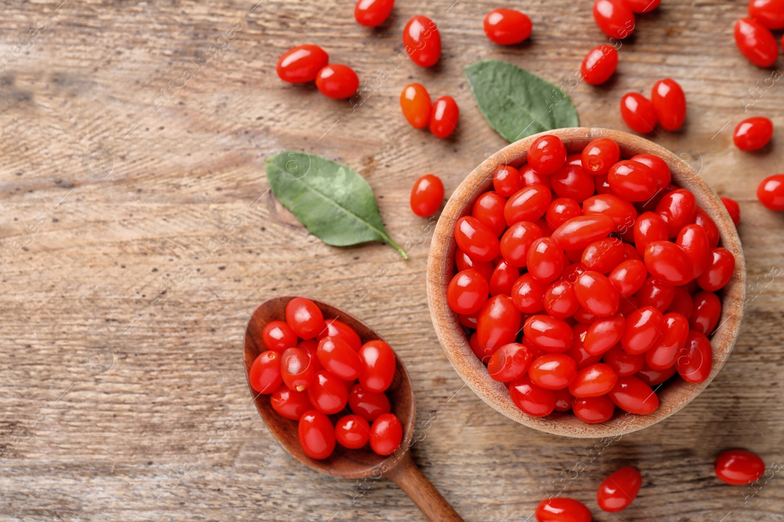 Photo of Fresh ripe goji berries on wooden table, flat lay