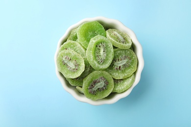 Photo of Bowl with slices of kiwi on color background, top view. Dried fruit as healthy food