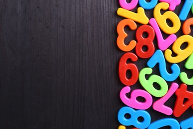 Photo of Colorful numbers on dark wooden school desk, flat lay. Space for text