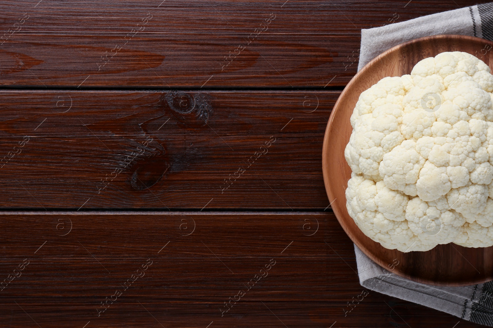 Photo of Plate with fresh raw cauliflower on wooden table, top view. Space for text