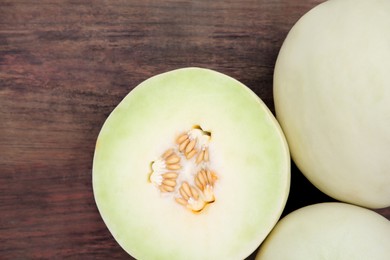 Whole and cut fresh ripe melons on wooden table, flat lay