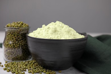 Photo of Mung bean flour in bowl and seeds on white marble table