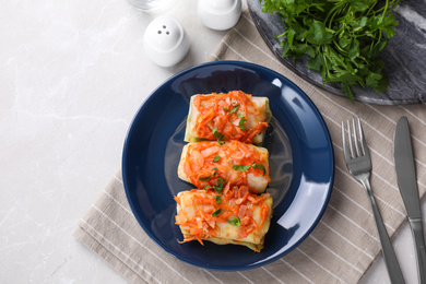 Photo of Delicious cabbage rolls served on light grey marble table, flat lay