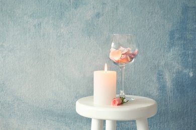 Candle with floral decor on table against color background