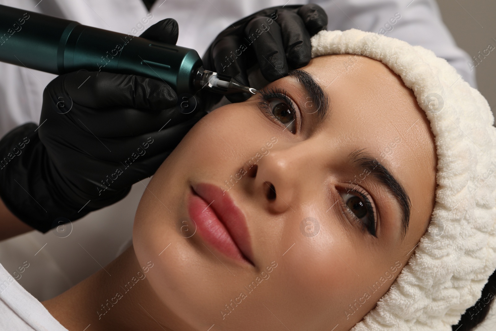 Photo of Young woman undergoing procedure of permanent eyeliner makeup, closeup