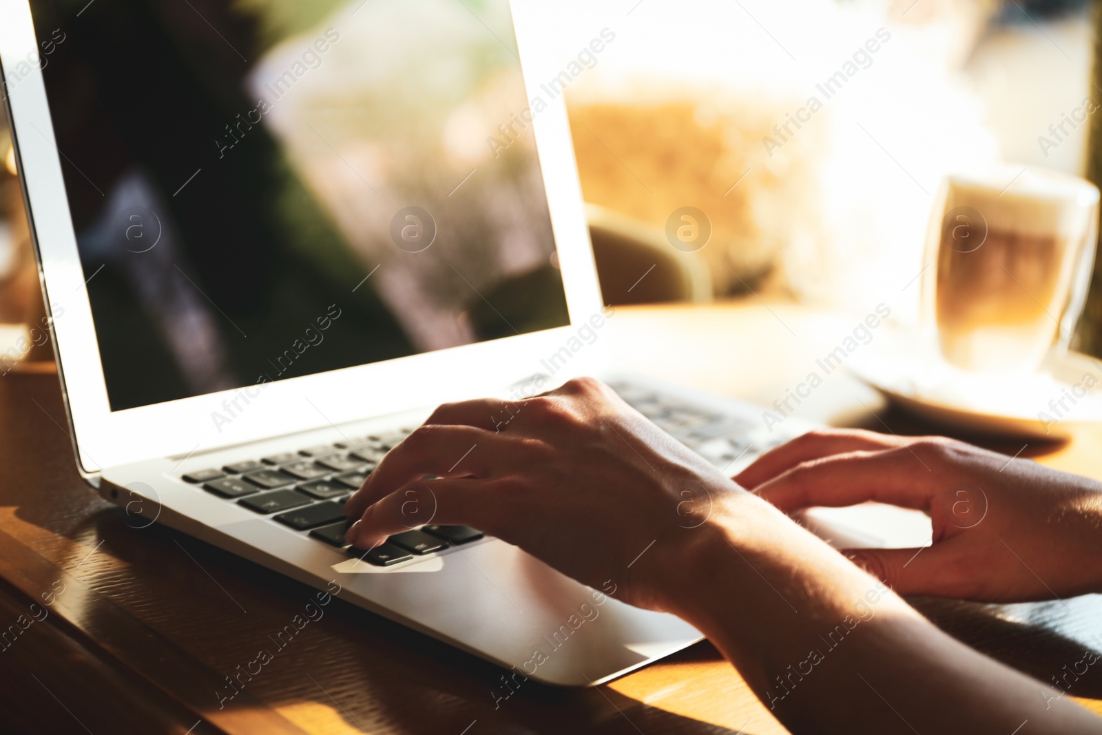 Photo of Woman using laptop at table, closeup of hands