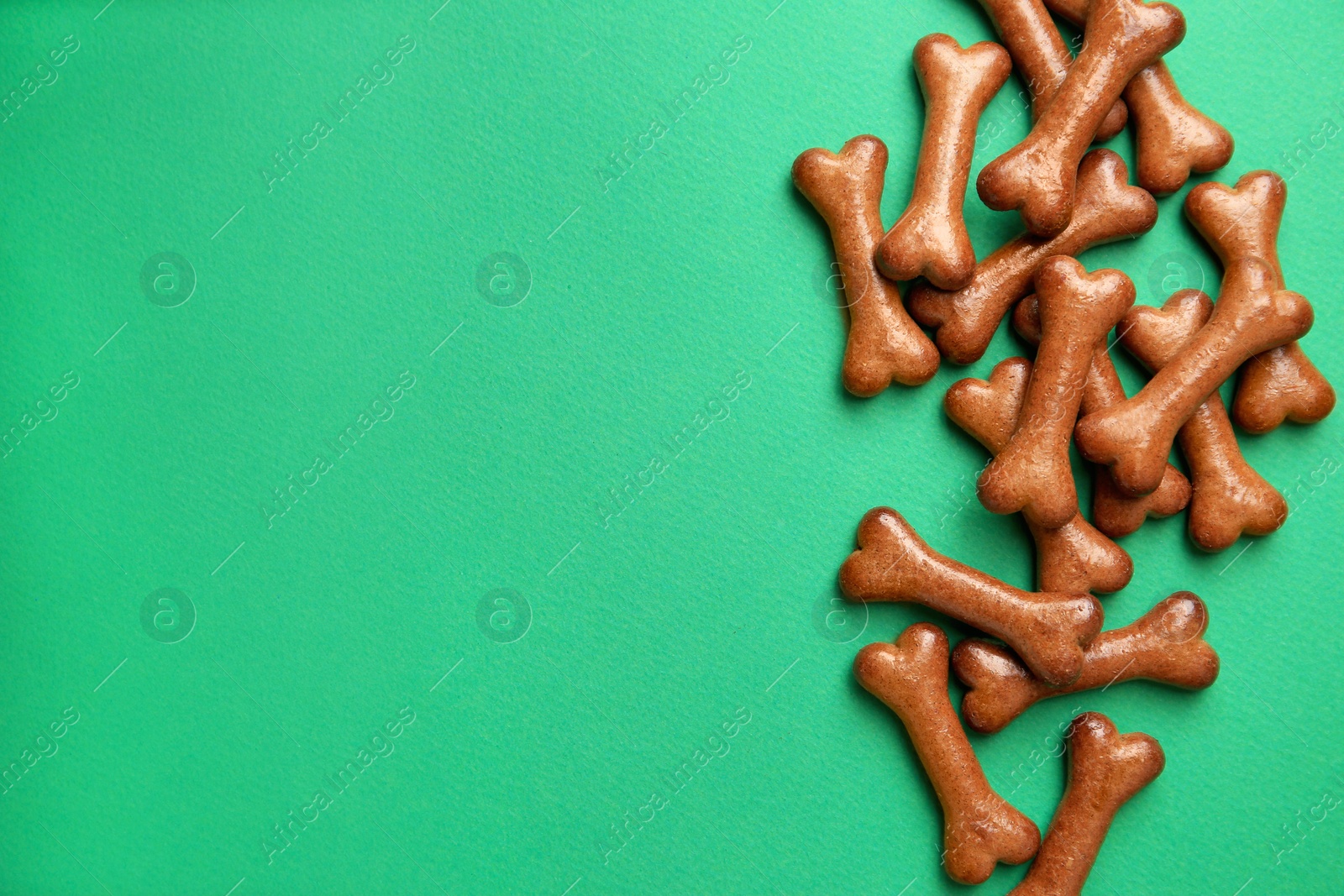 Photo of Bone shaped dog cookies on green background, flat lay. Space for text