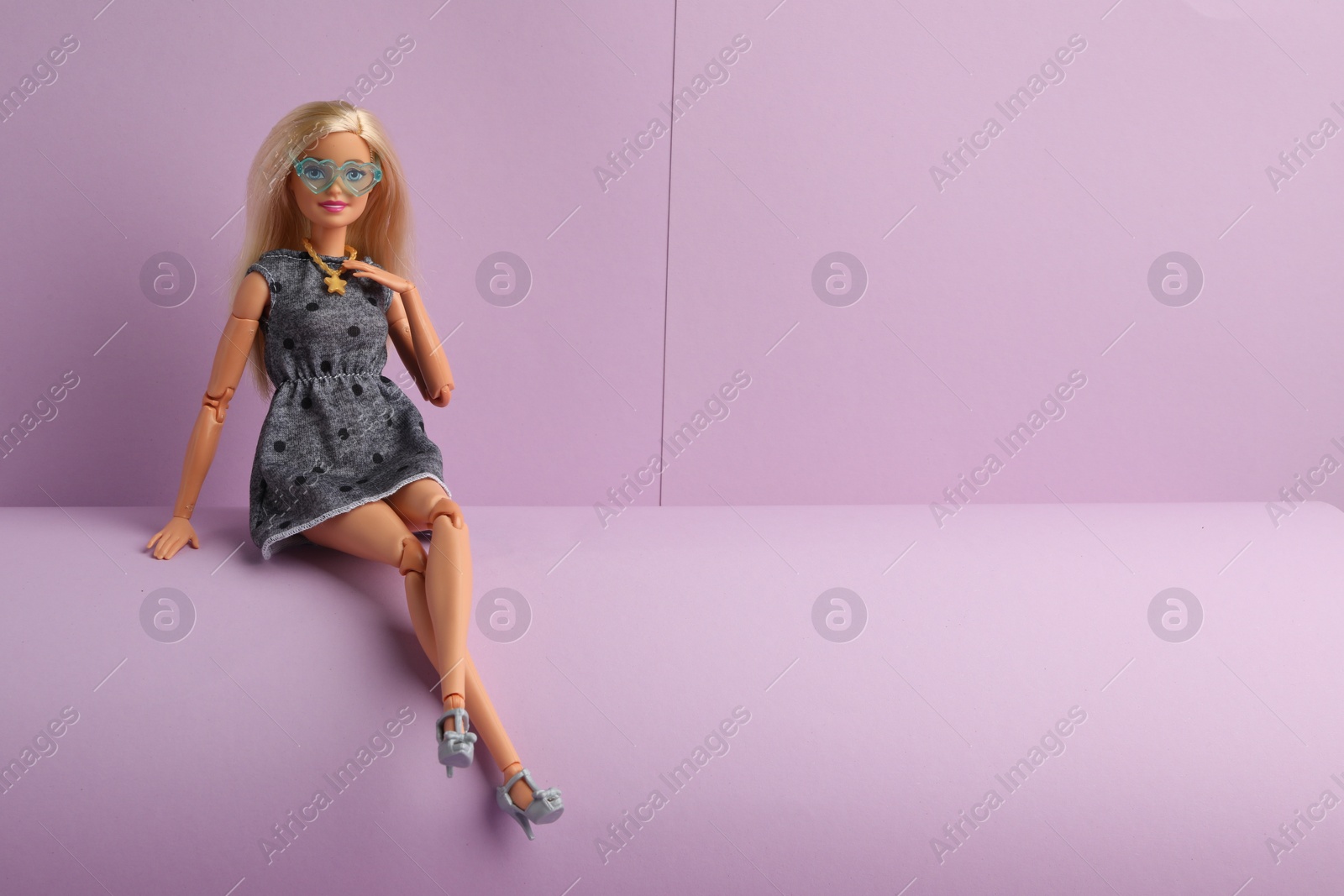 Photo of Mykolaiv, Ukraine - September 4, 2023: Beautiful Barbie doll with stylish eyeglasses sitting on lilac background, space for text