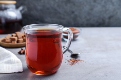 Photo of Freshly brewed rooibos tea on grey table. Space for text