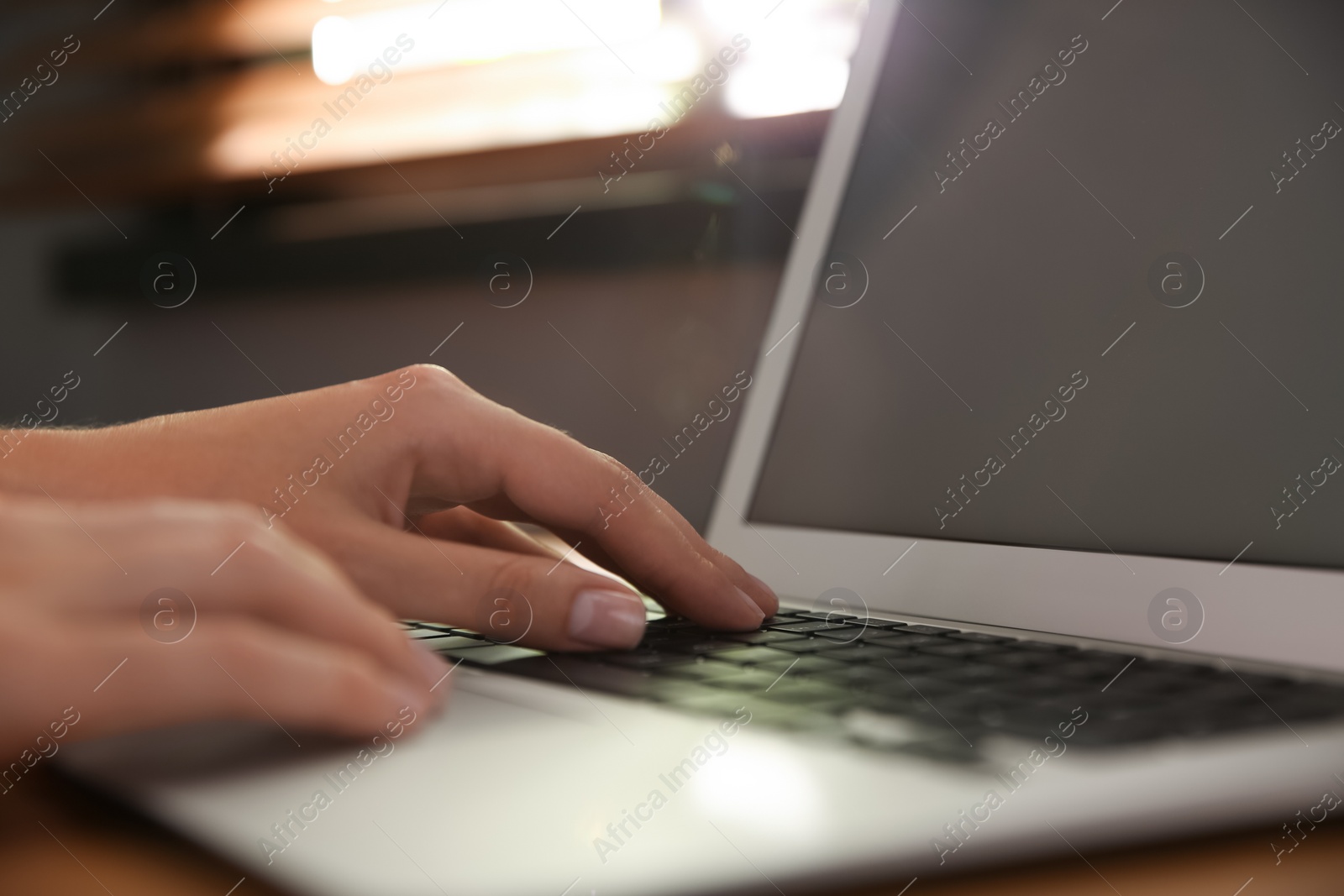 Photo of Woman using modern laptop at table indoors, closeup