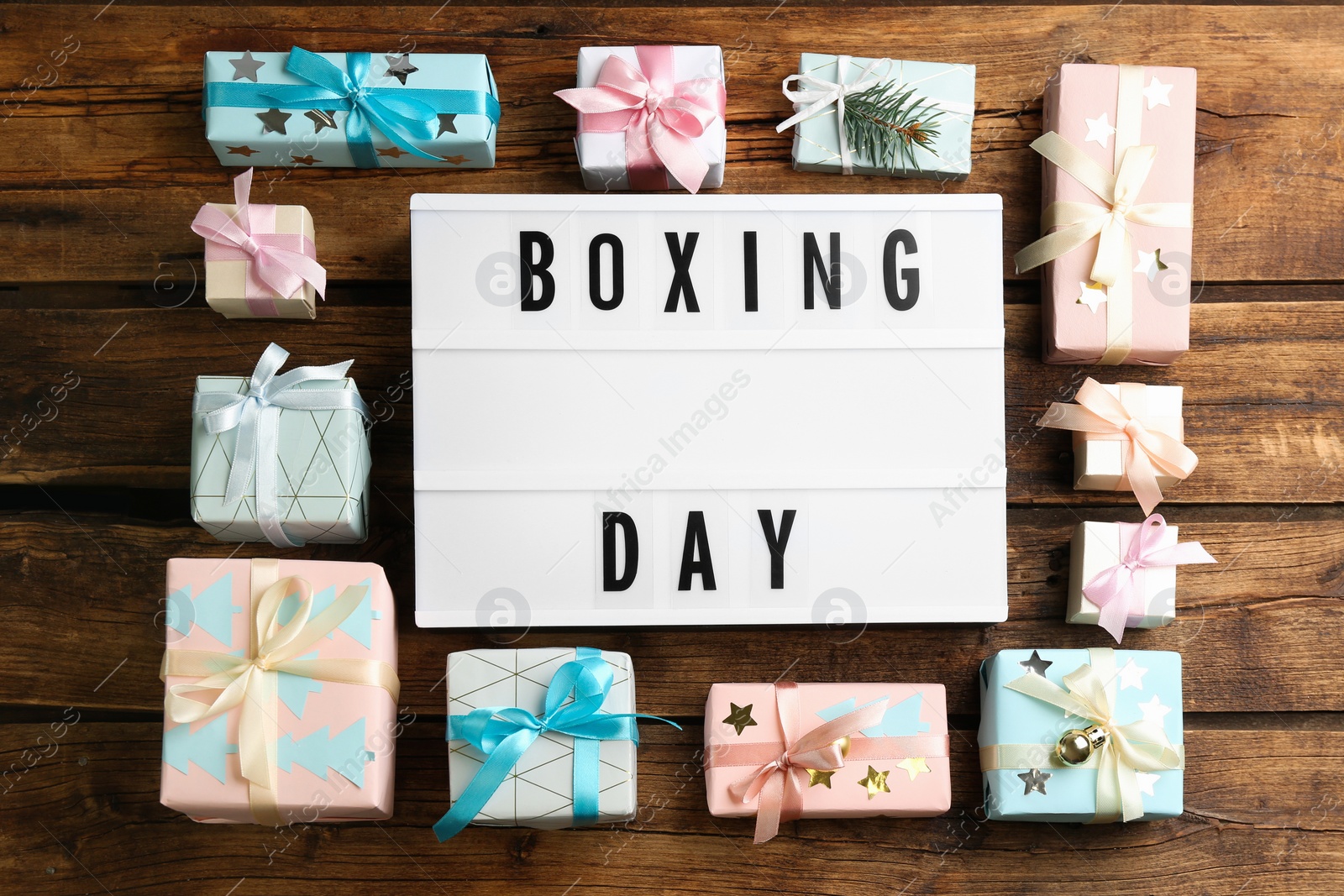 Photo of Lightbox with phrase BOXING DAY and Christmas decorations on wooden background, flat lay