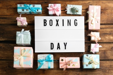 Lightbox with phrase BOXING DAY and Christmas decorations on wooden background, flat lay