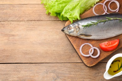 Photo of Board with delicious salted herring and ingredients on wooden table, flat lay. Space for text