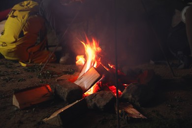 Man near bonfire outdoors in evening, closeup. Camping season