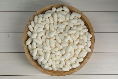 Photo of Silk cocoons in bowl on white wooden table, top view
