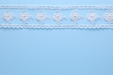 Photo of White lace on light blue background, top view. Space for text