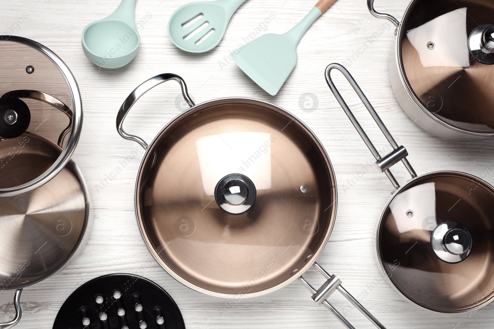 Photo of New cookware set and kitchen utensils on white wooden table, flat lay