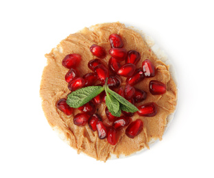 Photo of Puffed rice cake with peanut butter, pomegranate seeds and mint isolated on white, top view