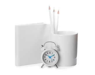 Photo of Holder with pencils, book and alarm clock on white background