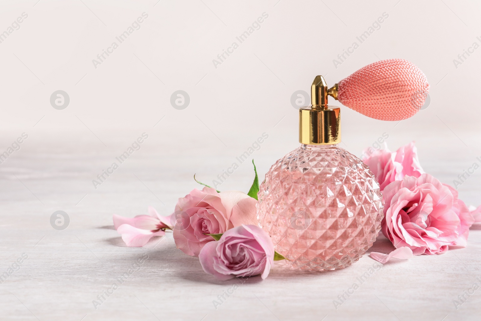 Photo of Vintage bottle of perfume and flowers on light background, space for text