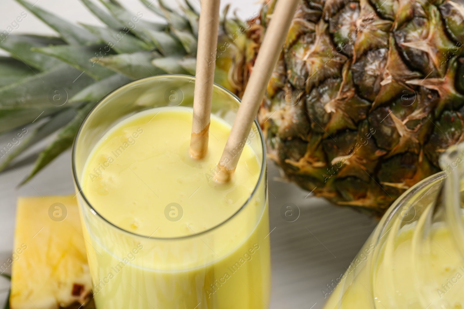 Tasty pineapple smoothie and fruit on white table, closeup Photo of Tasty pineapple smoothie and fruit on white table, closeup
