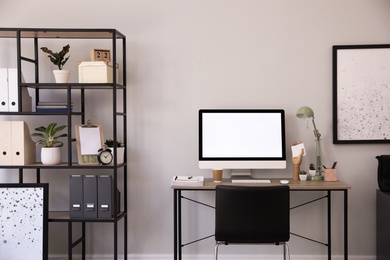 Photo of Comfortable office chair near desk with modern computer indoors