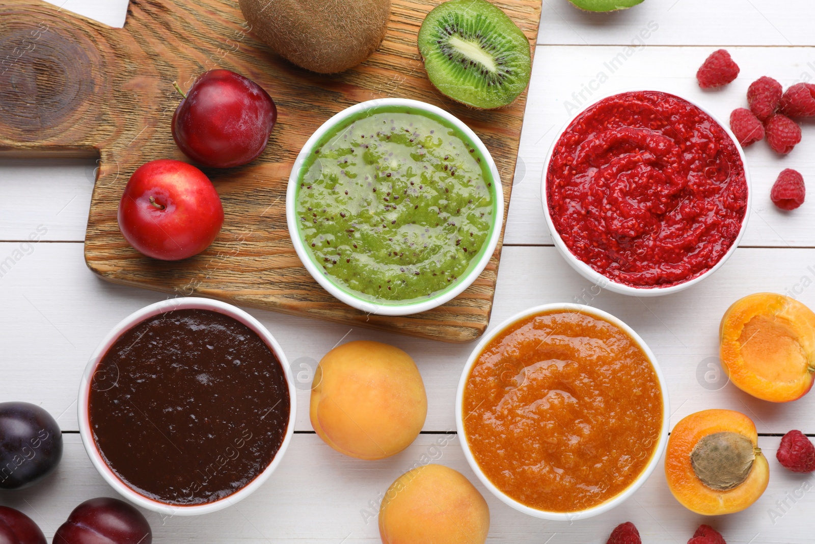 Photo of Different puree in bowls and fresh fruits on white wooden table, flat lay