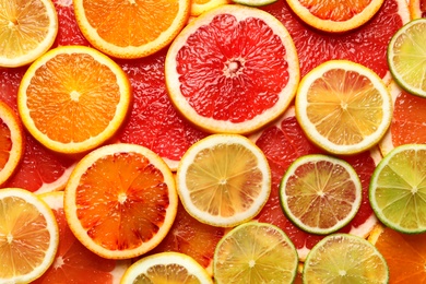 Photo of Slices of fresh citrus fruits as background, top view