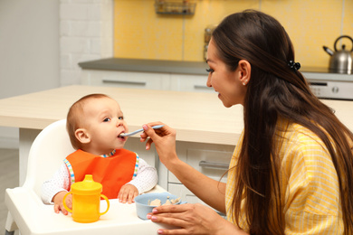 Young mother feeding her little baby at home