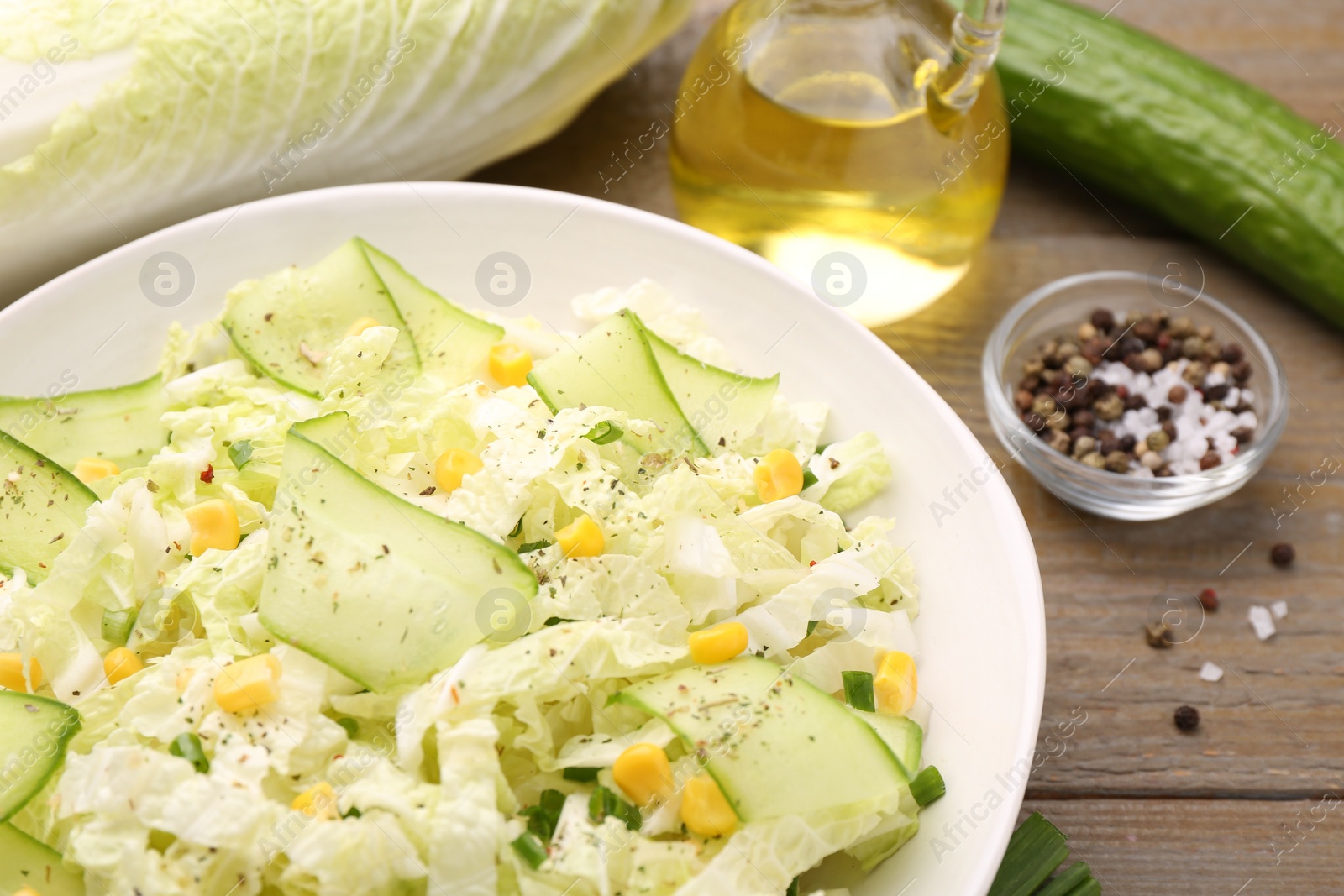 Photo of Tasty salad with Chinese cabbage, cucumber and corn in bowl on wooden table, closeup