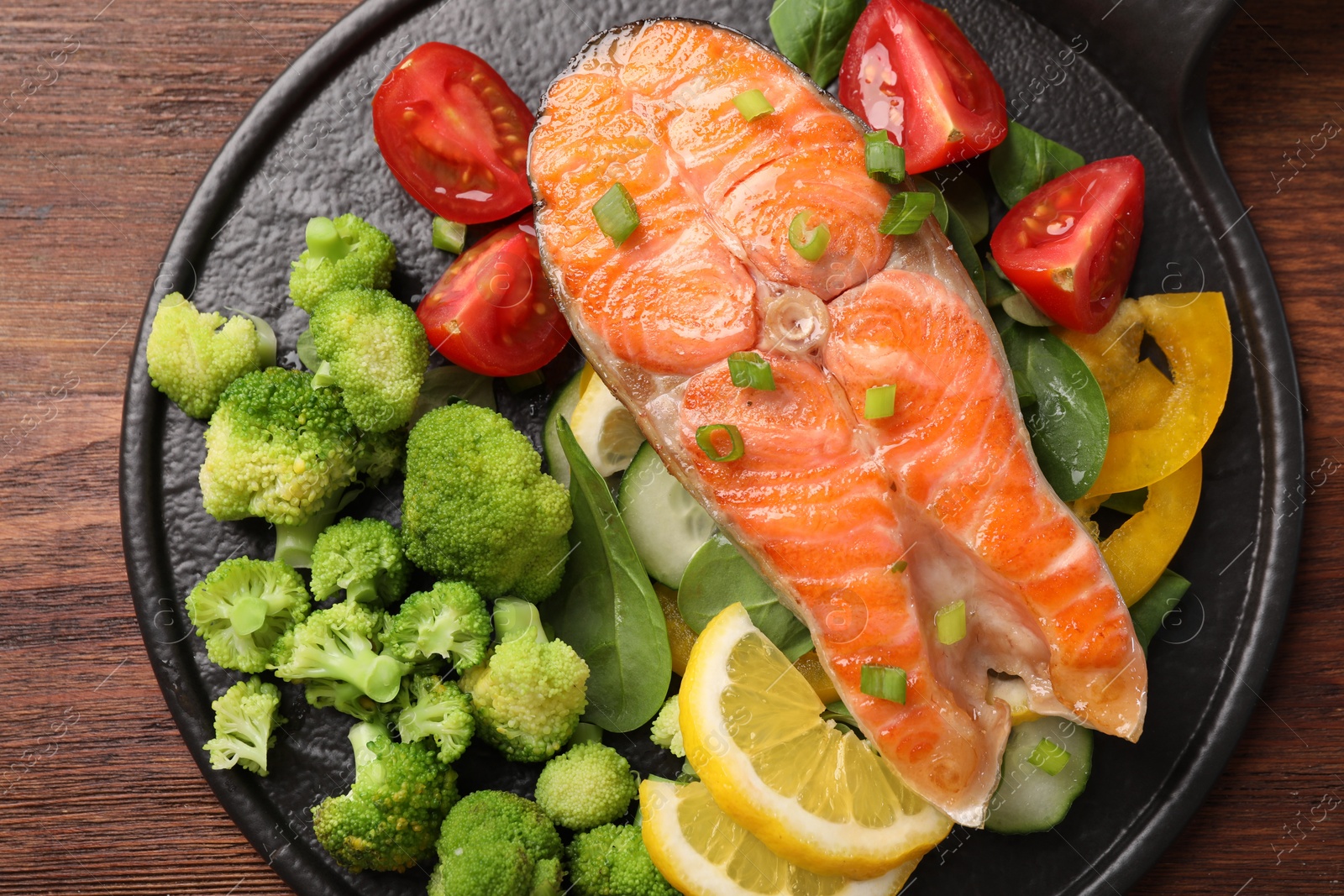 Photo of Healthy meal. Grilled salmon steak, spinach, lemon and vegetables served on wooden table, top view