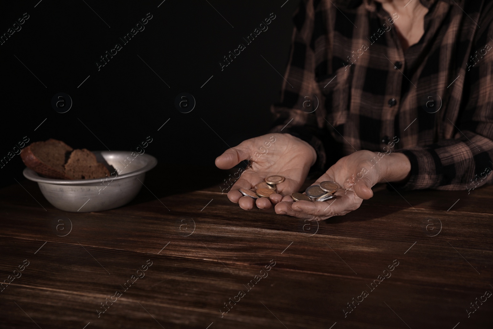 Photo of Poor mature woman holding coins at table, closeup. Space for text