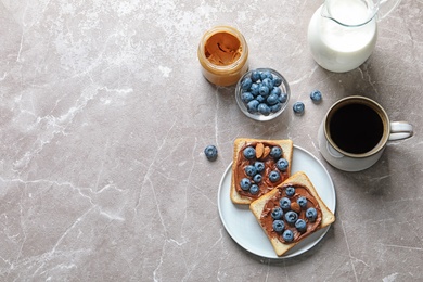 Flat lay composition with toast bread, blueberries, chocolate paste and cup of coffee on grey background