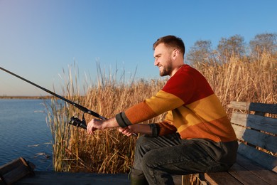 Photo of Fisherman with fishing rod at riverside on sunny day