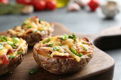 Photo of Board of baked potatoes with cheese and bacon on table, closeup