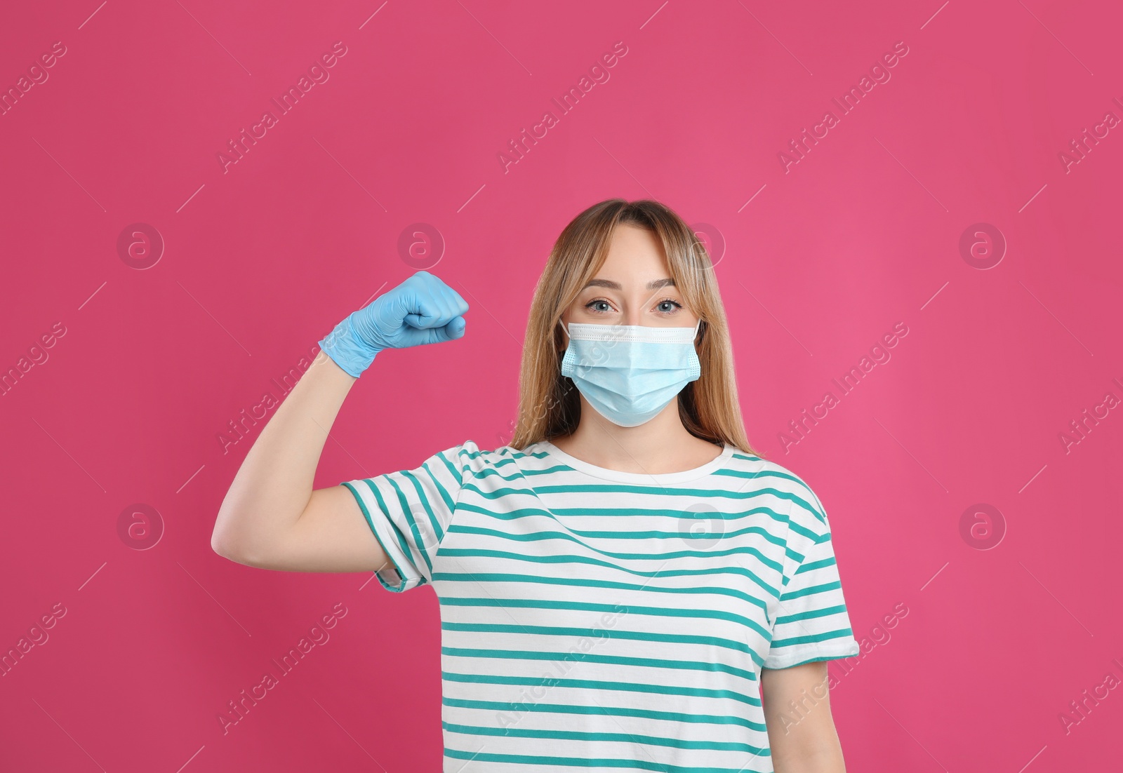 Photo of Woman with protective mask and gloves showing muscles on pink background. Strong immunity concept