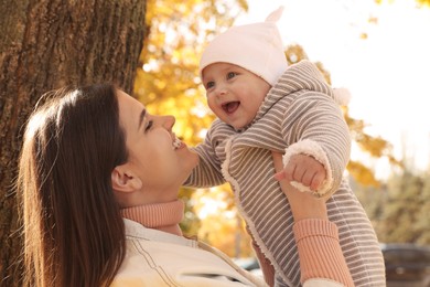 Happy mother with her baby daughter in park on sunny autumn day