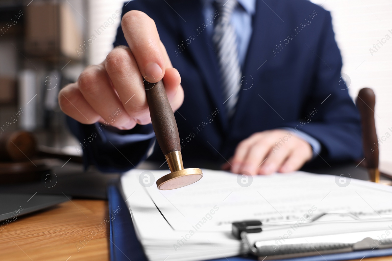 Photo of Notary stamping document at wooden table in office, closeup