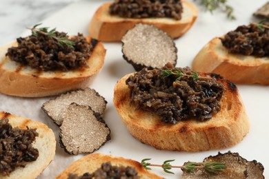 Photo of Delicious bruschettas with truffle sauce and thyme on white table, closeup